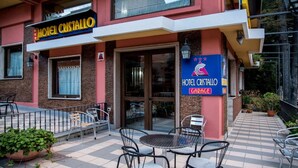 A hotel named 'Hotel Cristallo' with a visible entrance, outdoor seating area, and a sign indicating a garage. - Hotel Cristallo (Spezzano della Sila)