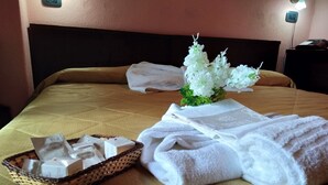 A neatly made bed with white towels, a basket of toiletries, and a small bouquet of flowers. - Hotel Cristallo (Spezzano della Sila)