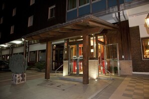 Ein Hotel mit Eingangsbereich, überdachter Vorhalle, Glasüren und einer Treppe zum Eingang.