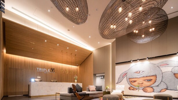 Eine moderne Hotelhalle mit einer Rezeption, einer Sitzecke und einem großen Wandgemälde.