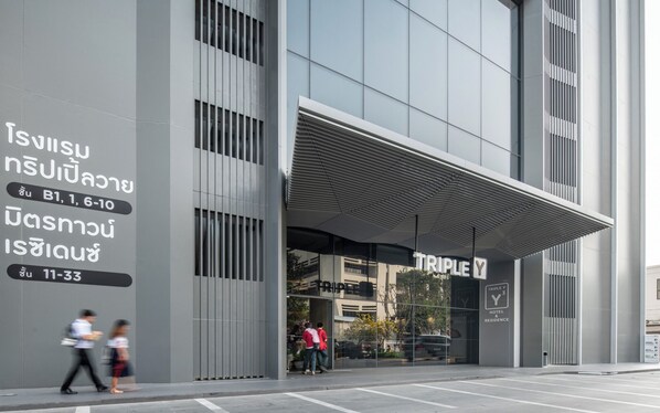 Uma entrada de hotel moderna com fachada de vidro ampla e área de acesso coberta.