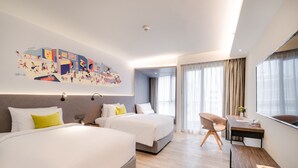 Ein Hotelzimmer mit zwei Betten, einem Schreibtisch, einem Stuhl und einem großen Wandbild.