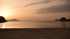 Une plage avec une promenade en bois menant à l’eau, une mer calme et des montagnes à l’horizon.