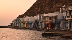 Un bâtiment situé sur la côte, doté de balcons et ayant une colline en arrière-plan.