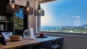 Une cuisine moderne avec un coin repas, une vue sur la mer et un balcon équipé d’une table et de chaises.