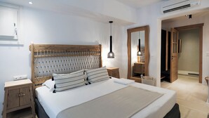 Une chambre moderne avec une tête de lit en bois, un grand lit avec une literie blanche, une table de chevet, un luminaire suspendu et un miroir.