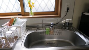 A kitchen with a stainless steel sink, a window with a view, and a vase with flowers on the windowsill. - 2 min. to Asakusa line - Quiet area (大田区)