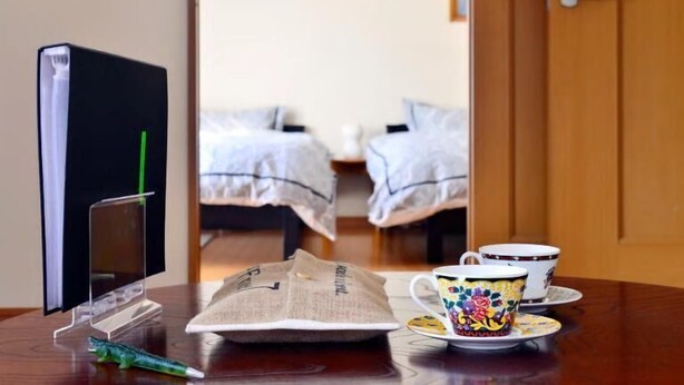 A hotel room with a bed, a coffee table with a newspaper, a cup, and a TV on a stand. - 2 min. to Asakusa line - Quiet area (大田区)