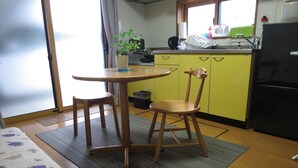 A small kitchen with a dining table and two chairs, a refrigerator, and a window with curtains. - 2 min. to Asakusa line - Quiet area (大田区)