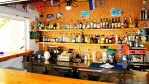 Uma área de bar com várias prateleiras de garrafas de bebidas, um caixa registradora e uma máquina de café.