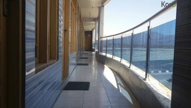A corridor with a view of a body of water, wooden walls, and a tiled floor. - Hotel River side and Restaurant (Swat)