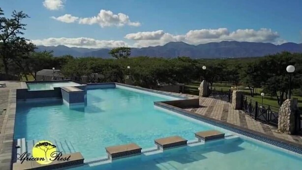 A rectangular swimming pool with a clear view of mountains in the background. - African Rest Lodge (Barberton)