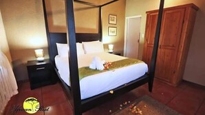 A four-poster bed with white linens, a nightstand with a lamp, and a wooden wardrobe. - African Rest Lodge (Barberton)