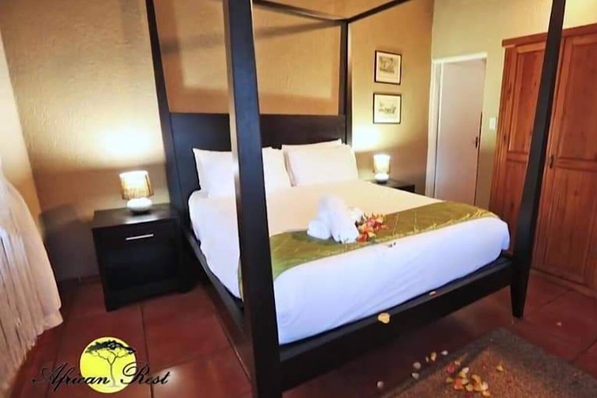 Un lit à baldaquin avec du linge de lit blanc, une table de chevet avec une lampe et une armoire en bois.