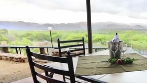 A table set outdoors with a view of a green landscape. - African Rest Lodge (Barberton)