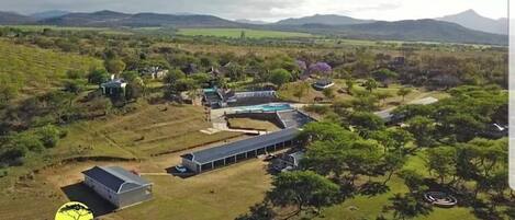An aerial view of a property with multiple buildings, including a long structure with a flat roof, possibly a restaurant or communal area, and several smaller buildings with distinct roofs.
