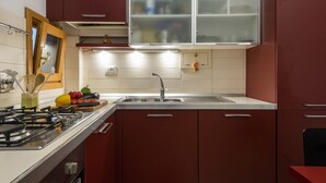 Une cuisine équipée d’une cuisinière à gaz, d’un évier et d’une fenêtre située au-dessus du plan de travail.