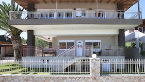 A two-story building with a balcony, stone wall, and a palm tree in the foreground. - PEGGY'S VILLA 50 SQM (Κινέτα)