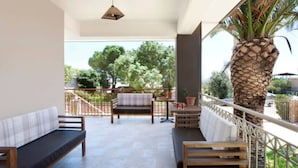A balcony with a wooden bench, a table, and a potted plant. - PEGGY'S VILLA 50 SQM (Κινέτα)
