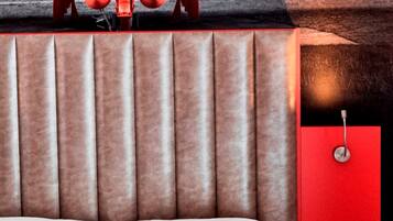 Une pièce avec un lit, un mur rouge et une fresque représentant un avion rouge.