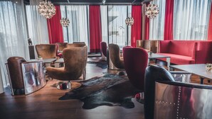 Un espace détente moderne avec des fauteuils en cuir, un canapé rouge et une table en bois.