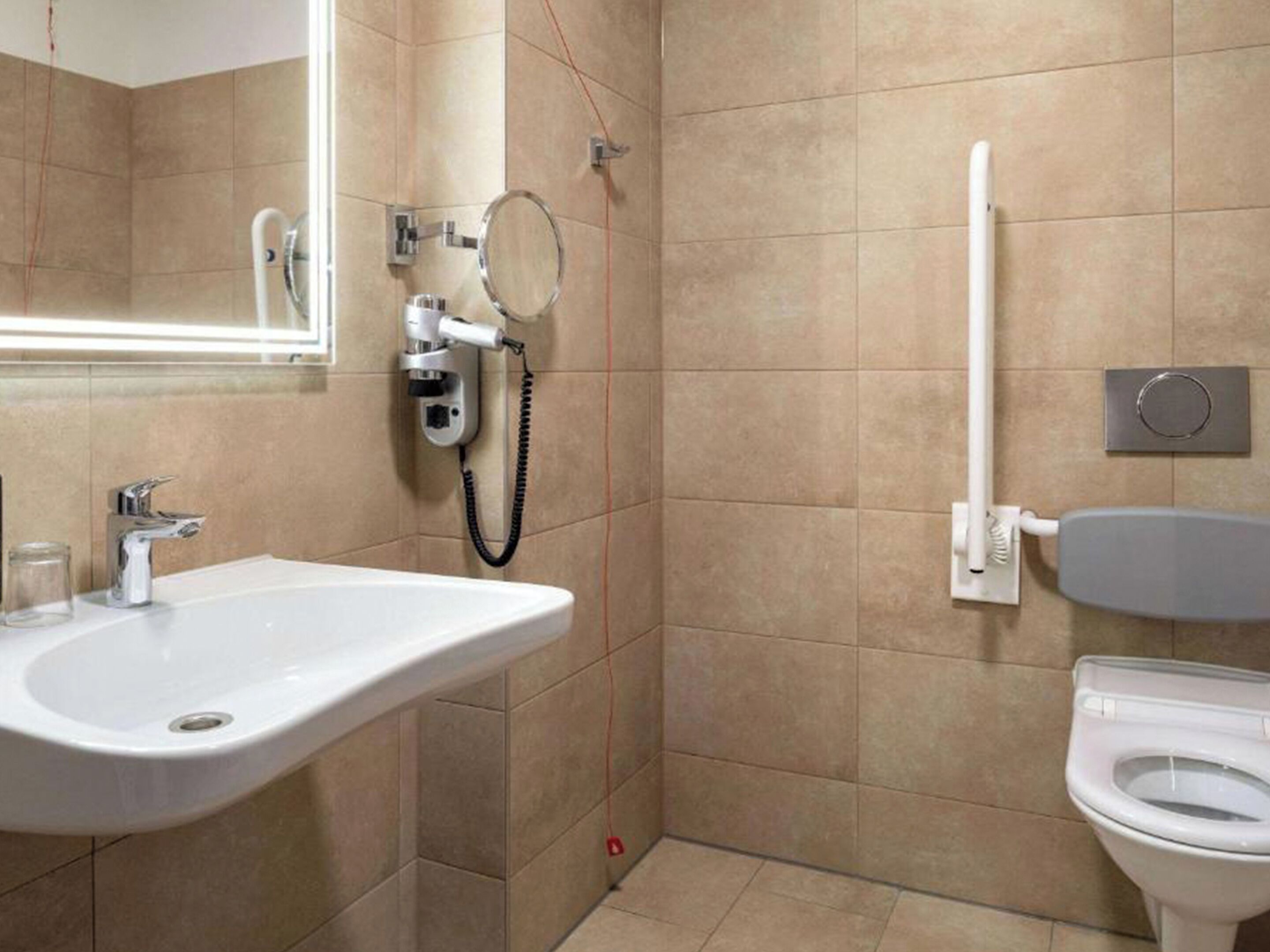 A bathroom with a sink, mirror, toilet, and shower.