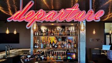 A bar area with a neon sign reading "departure" and a variety of liquor bottles on shelves.
