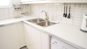 Een moderne keuken met witte kasten, roestvrijstalen spoelbakken en een vaatwasser.