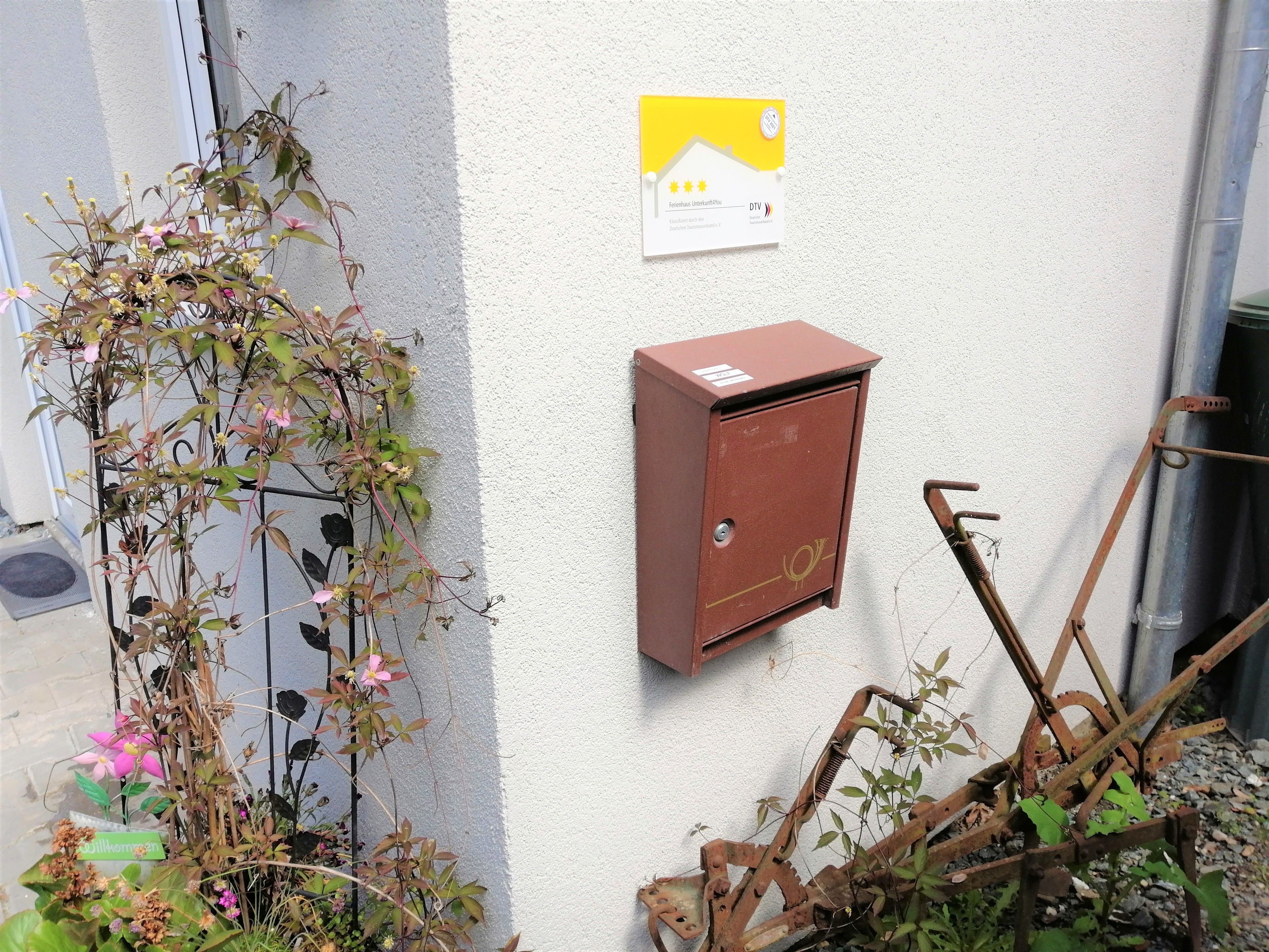 A utility box mounted on a wall, a sign with a rating, and a metal structure leaning against the wall.