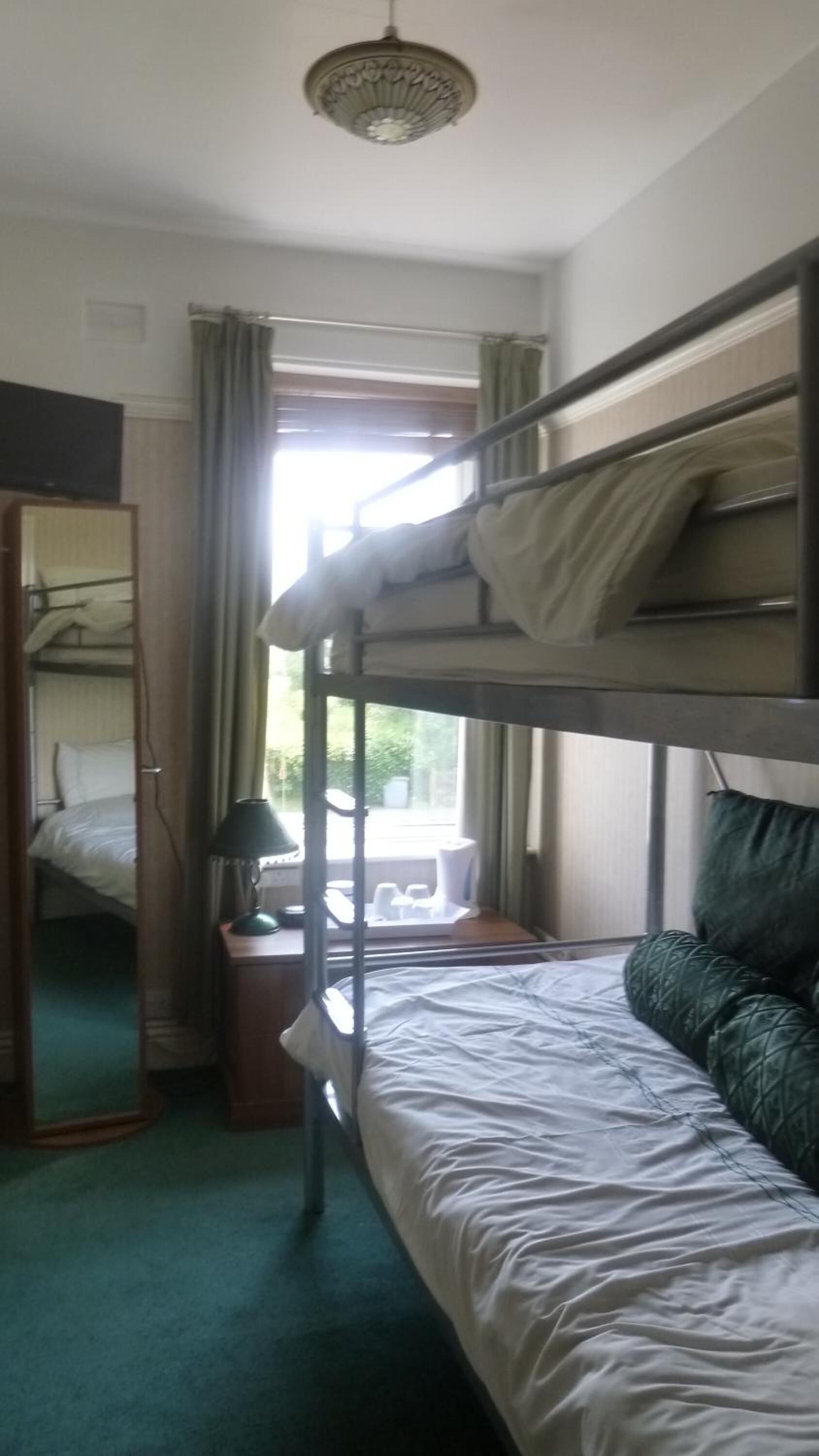 Habitación con literas, un escritorio y un espejo.