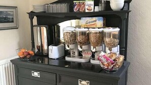 A buffet setup with various food items and condiments on a dark wooden cabinet. - Manor View Guest House (Whitby)