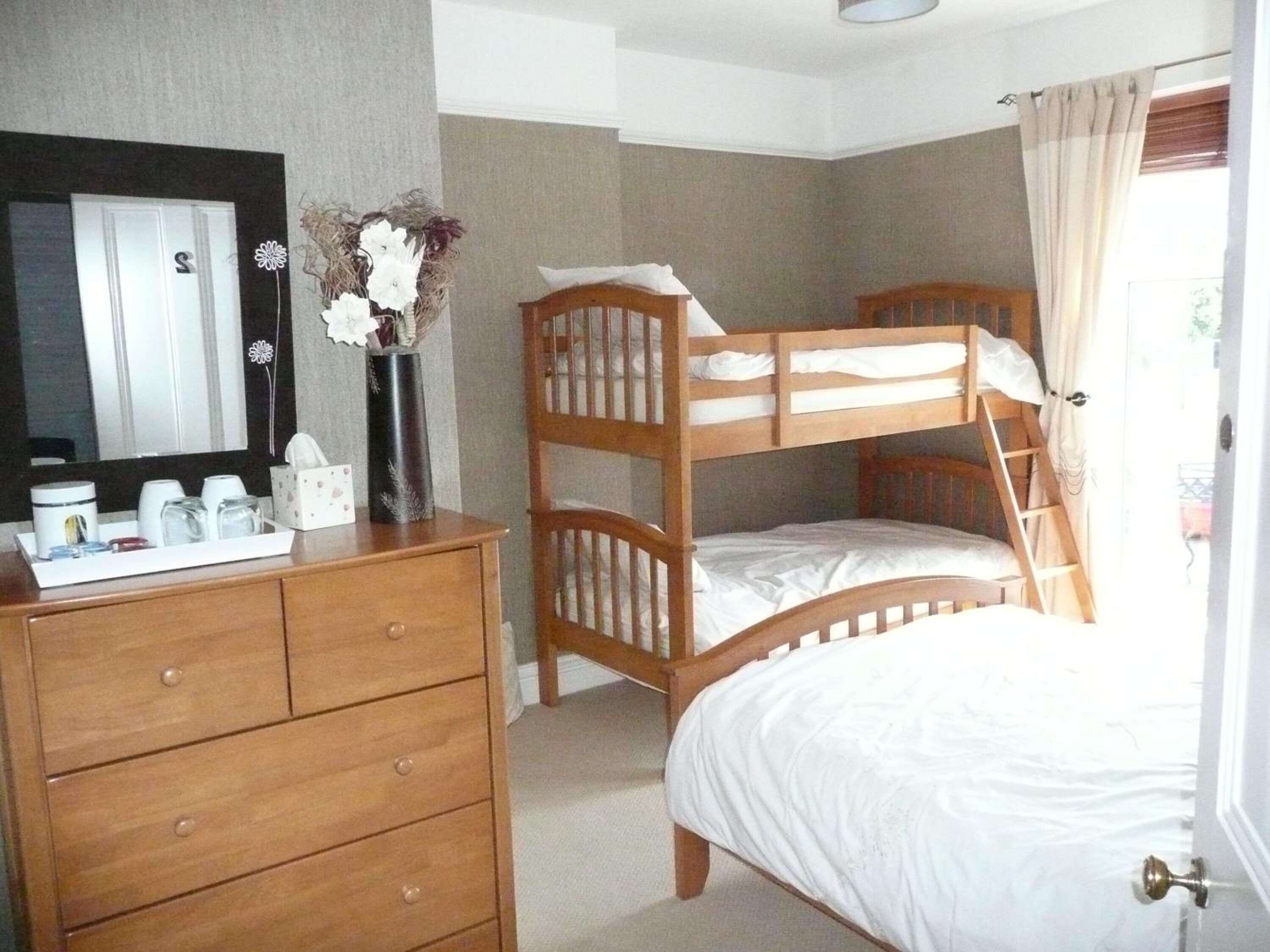 A bedroom with a bunk bed, a dresser with toiletries, and a mirror.