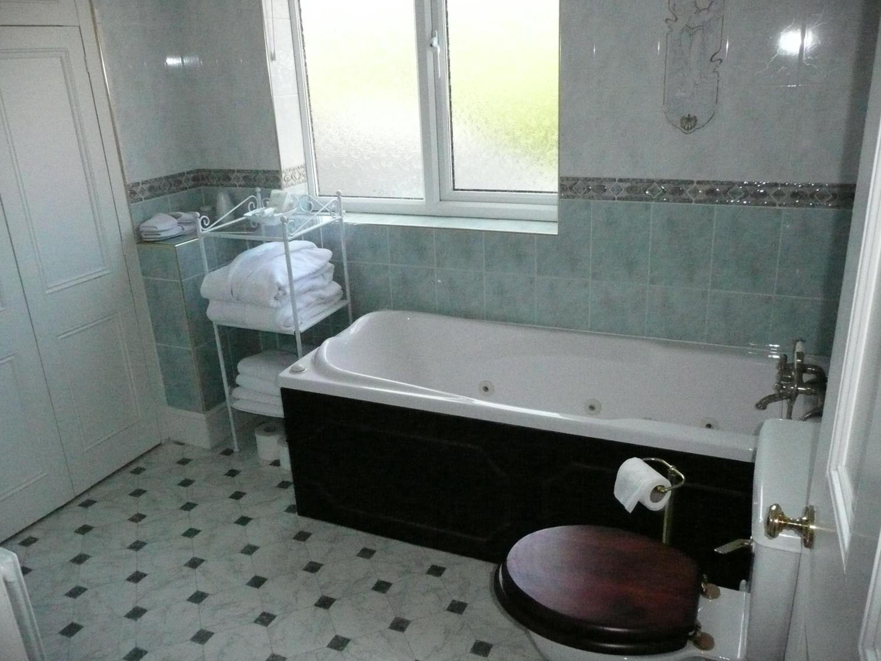 Un baño con bañera, inodoro y ventana.