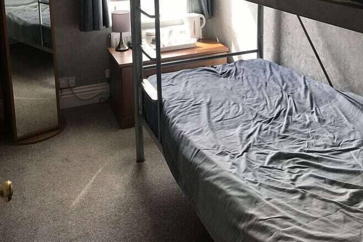 A bunk bed room with a desk and a window with curtains.