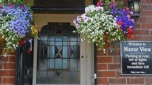A building with a sign reading "Manor View Quality Accommodation" and a welcome sign with parking instructions. - Manor View Guest House (Whitby)