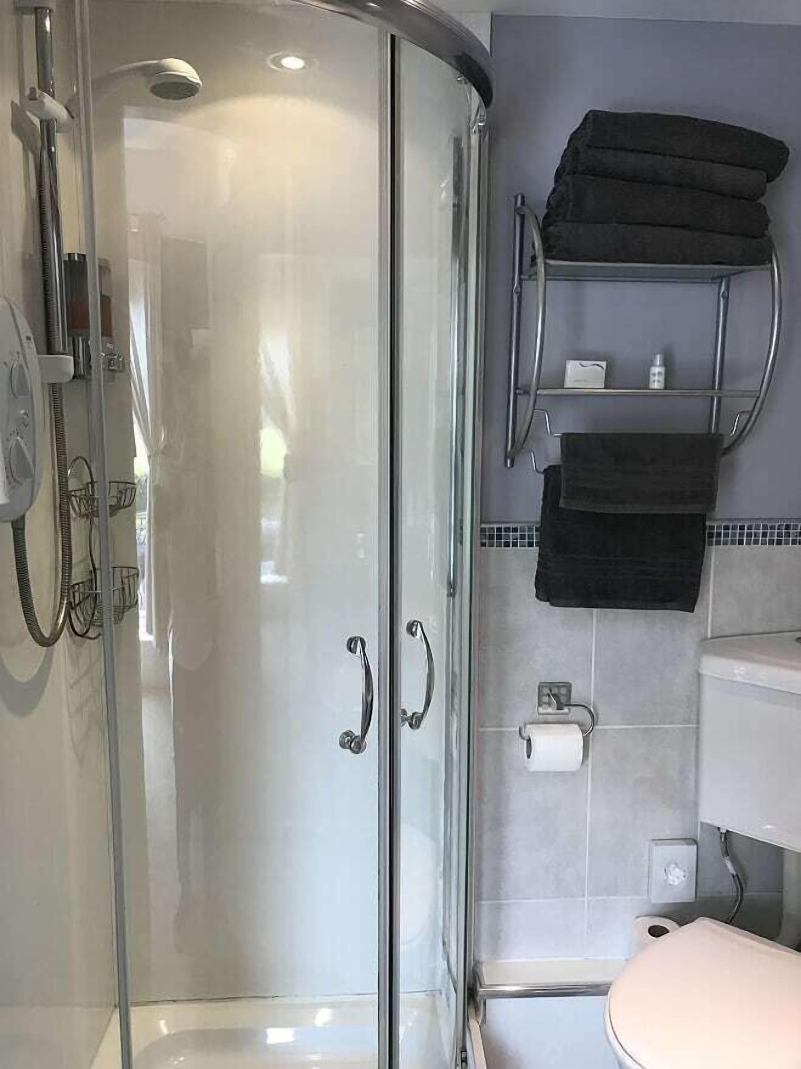 Ein modernes Badezimmer mit einer Duschkabine, einer Toilette und einem Handtuchhalter.