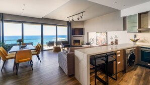 Une cuisine moderne dotée d’un grand îlot central, d’un coin repas offrant une vue sur la mer et d’un salon agrémenté d’une chemin ée.