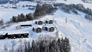 Un centro de esquí cubierto de nieve con varias edificaciones de estilo chalet, remontes y una pista de esquí serpenteante.