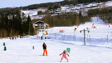 Un centro de esquí con telesilla, pistas cubiertas de nieve y edificios al fondo.