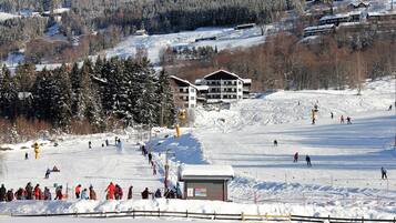 Estació d'esquí amb un gran refugi, pistes d'esquí i una muntanya boscosa de fons.