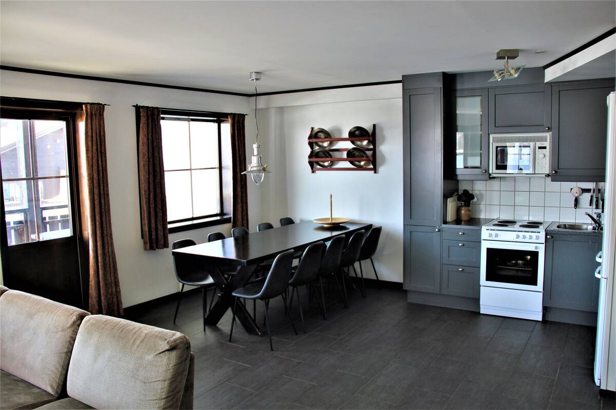 Una cocina moderna con armarios grises, una estufa blanca y una mesa de comedor con sillas.