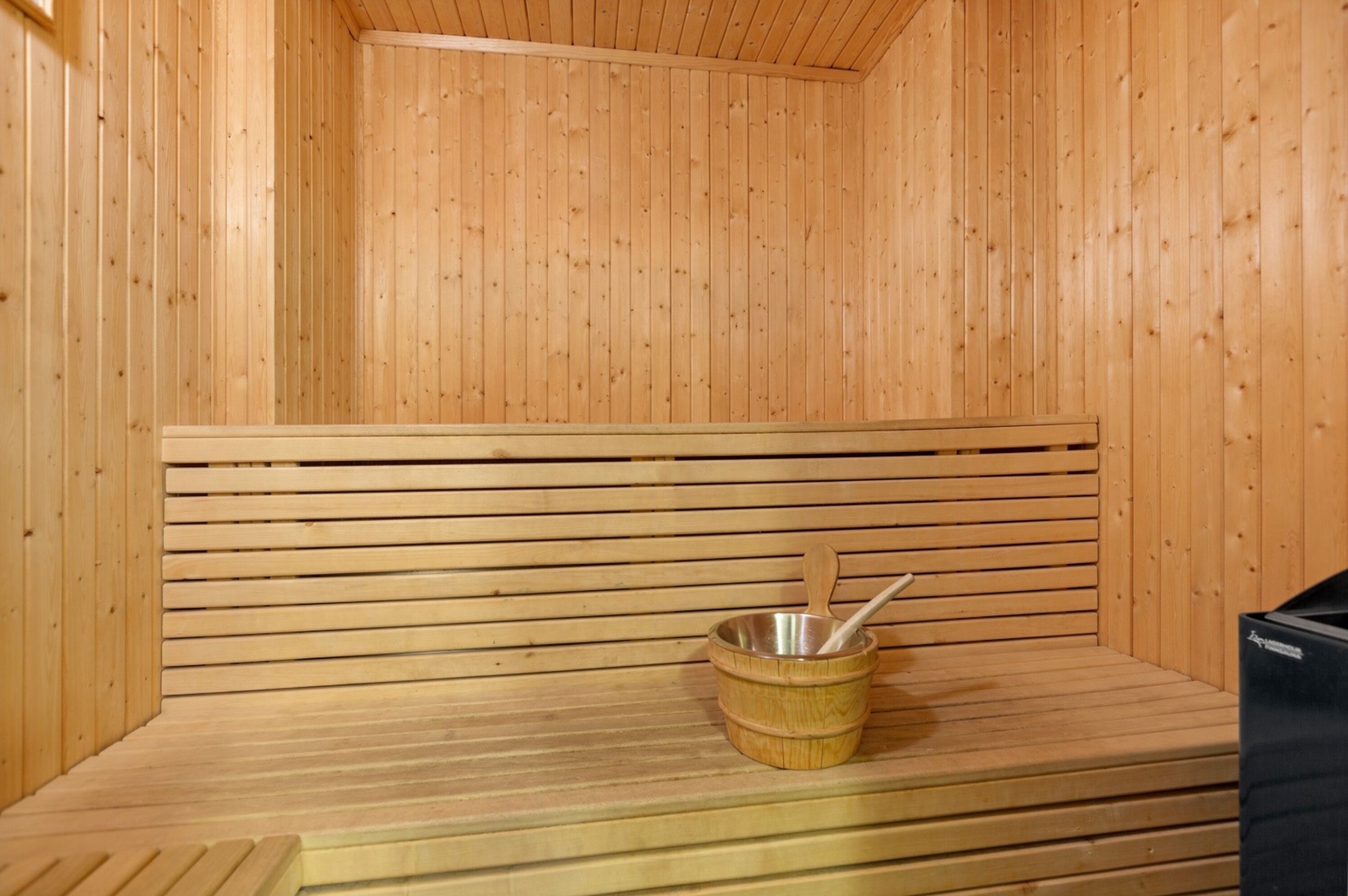 Una sauna con panche in legno e una vasca in metallo con una schiuma di legno.