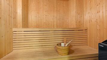 Una sauna con panche in legno e una vasca in metallo con una schiuma di legno.