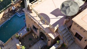 A courtyard with a pool, a staircase, and a building with a circular roof structure. - Gîte d'étape Imsker (Marrakech)