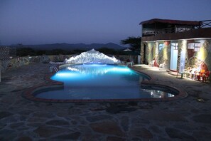 Una piscina al aire libre, sombrillas, sillones reclinables de piscina