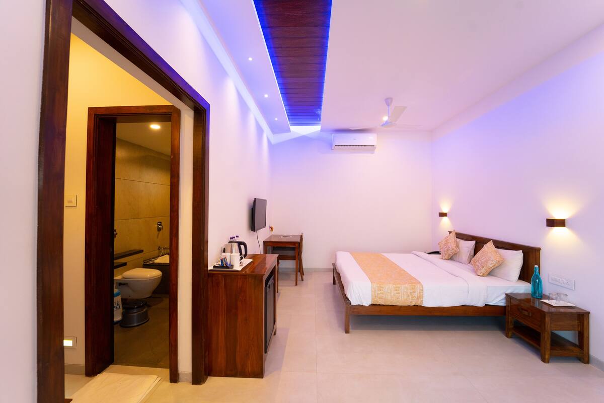 A bedroom with a bed, bedside tables, a desk, and a television.