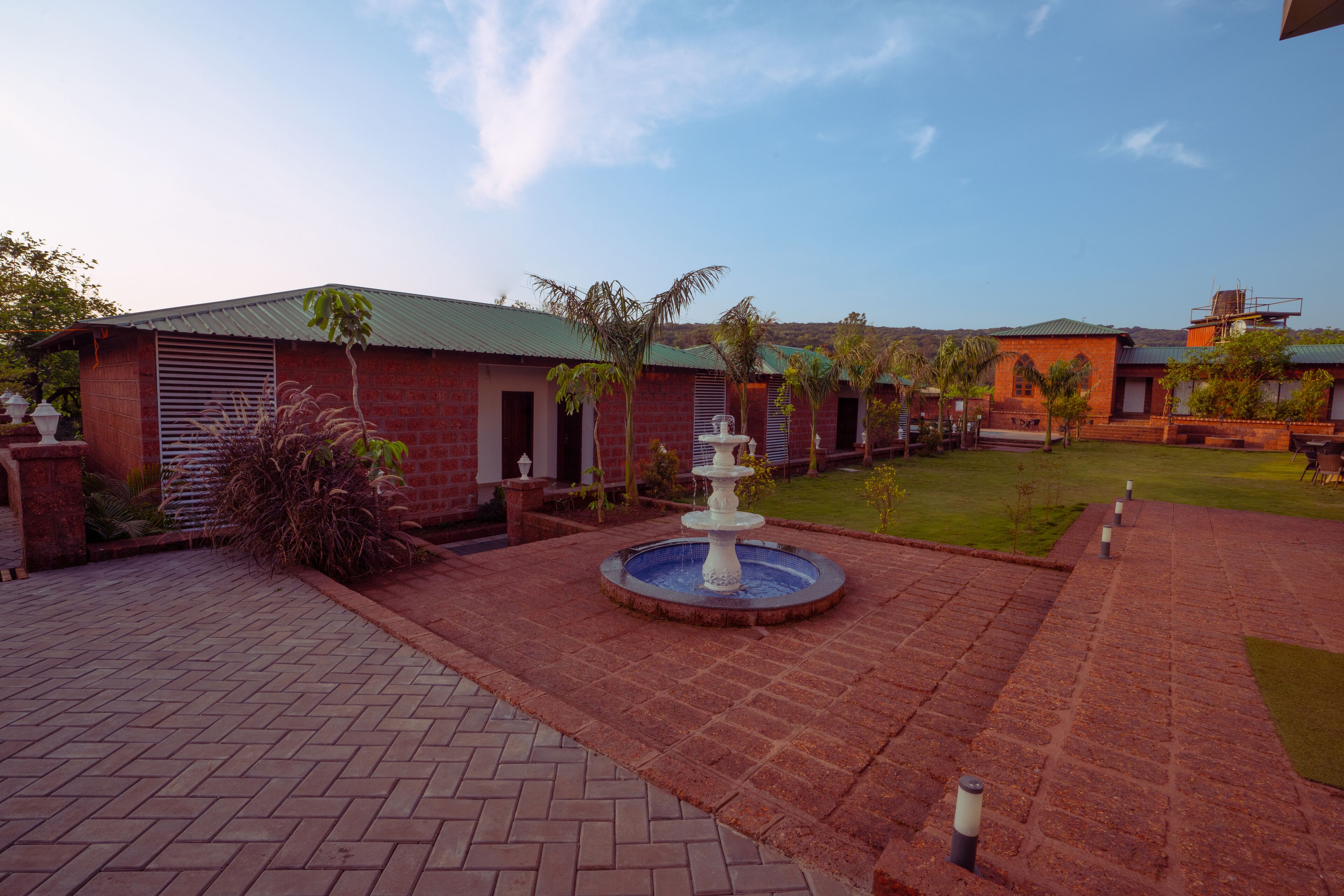 A courtyard with a fountain, brick pathways, and buildings with green roofs.