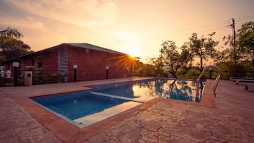 Alberca al aire libre, sombrillas en la alberca y camastros