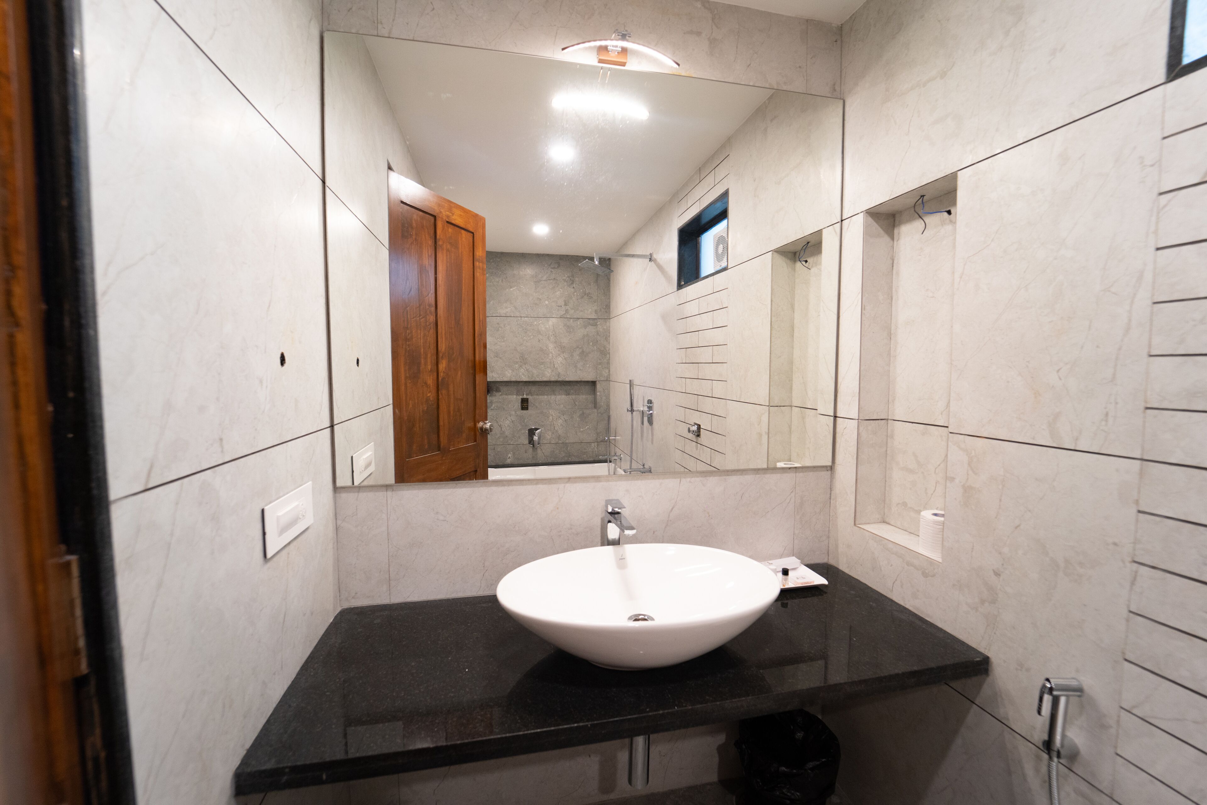 A modern bathroom with a white sink, black countertop, and a wooden cabinet.