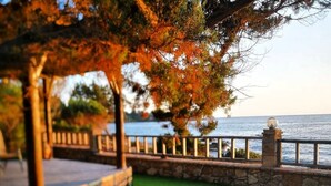 A stone pathway leading to a grassy area with a view of the sea.